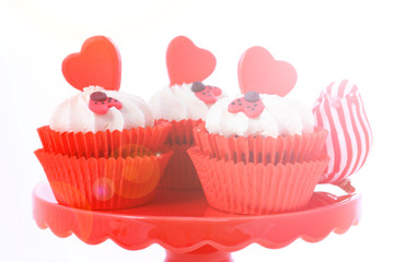 Red and white Valentine's cupcakes with hearts and love bug decorations with lens flare.