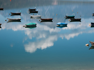 small fishing boats on the lake where the blue sky and white clouds are reflected