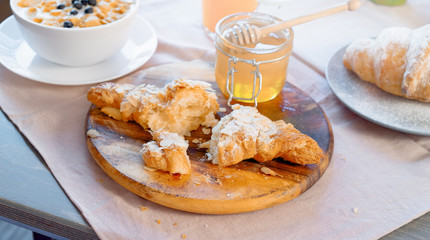 Croissant, honey jar and orange juice on wooden cutting board. Healthy breakfast.
