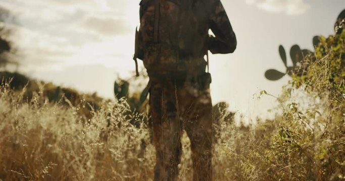 Bowhunter walks through dreamy golden grassland