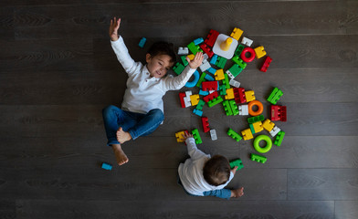 Two happy baby playing with toy blocks.