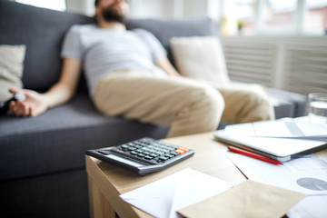 Calculator and financial papers on table on background of dead man on sofa