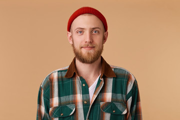 Attractive young man in studio looking at camera. Portrait of a normal guy with broad in red hat...