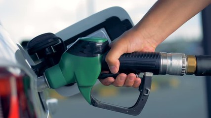 An automobile is getting refueled by a petrol pistol 