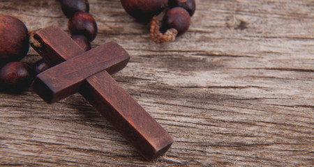Close up rosary against wooden board background as symbol of salvation and eternal life. Religion tradition.