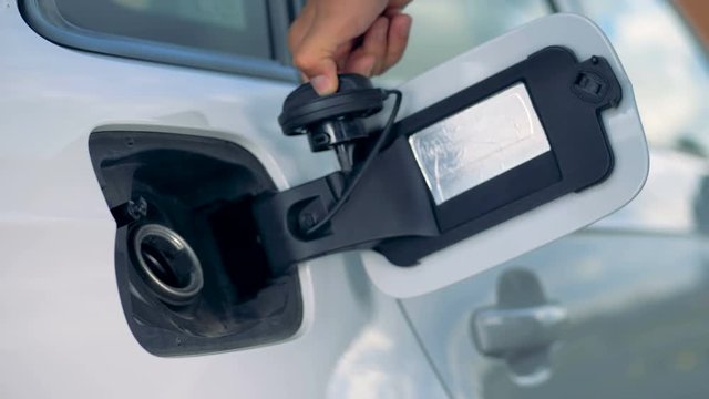 A person opens car's tank and starts refueling process