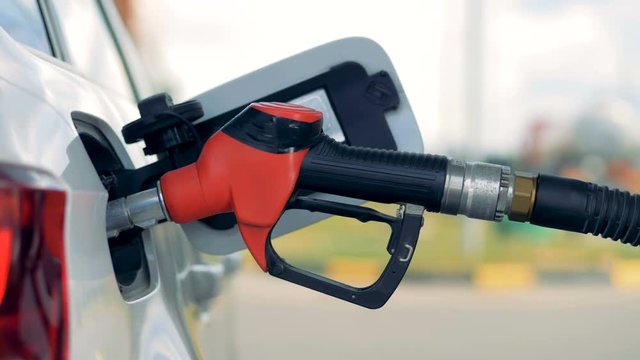 Side view of a petrol nozzle inserted into automobile's tank