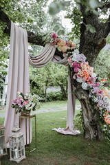 Wedding ceremony. A very beautiful wedding arch on the tree is decorated with many fresh beautiful...