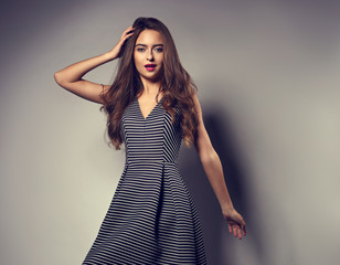 Happy smiling woman posing in fashion stripped white black dress on grey background with empty space.