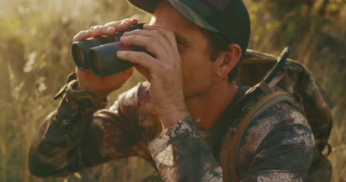 Hunter raising his binoculars searching for his next target