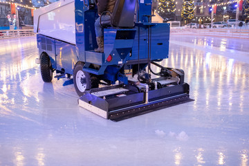 A machine for restoring or smoothing ice rides on an ice rink in the evening.