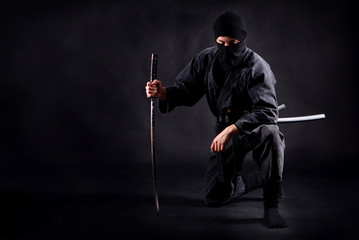 Ninja samurai crouched on one leg  and propped on a sword © Dmytro
