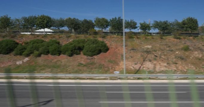 View from the train window to the empty Attiki Odos highway privately owned toll motorway, buildings and mountains while approaching to the Athens International Airport