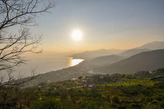 Backlight panoramic view of Borgio Verezzi with the coastal city of Pietra Ligure and Loano at sunset, Liguria, Italy