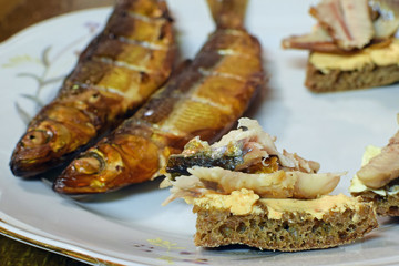 Rye bread with smoked vendace and cream cheese. Whole fishes on background.