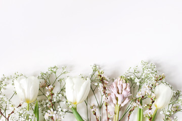 Easter floral frame, web banner. Spring wedding, birthday composition with pink hyacinth, cherry blossoms, white tulips and baby's breath flowers. White table background. Flat lay, top view.
