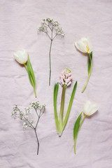 Spring, Easter floral botanical composition. White Gypsophila, tulips and hyacinth flowers lying on pink linen tablecloth background. Styled stock photo. Vertical flat lay, top view.