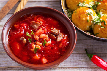 Soup borscht made with vegetables, meat, bean and beet root. Buns Pampushky - Ukrainian garlic bread. Bread rolls with garlic and parsley in baking dish