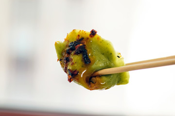 Chopsticks holding a vegetarian dumpling