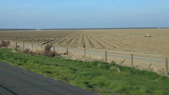 Slow motion passenger view. Passing ploughed fields ready for planting. Fresno County, California, USA.