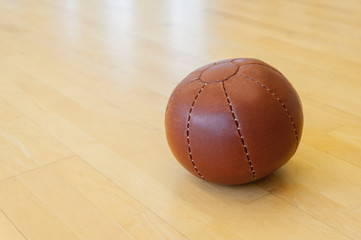 Brown medicine weight ball on wooden floor. Crossfit ball