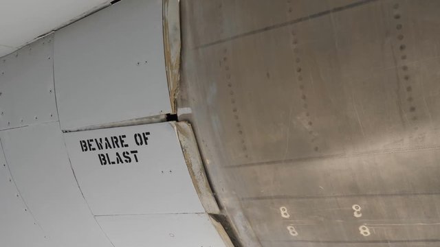 Pan from jet engine cowling to warning BEWARE of BLAST. F 14 Fighter jet.