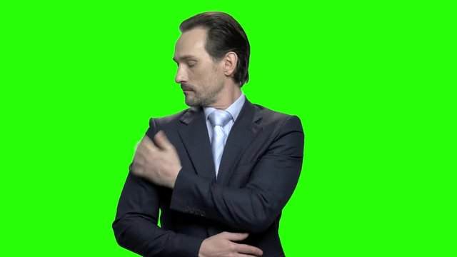 Handsome presentable mature business man preens himself. Green hromakey background for keying.