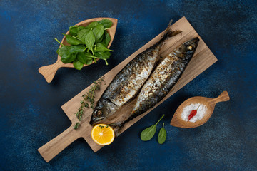 Baked mackerel fish on blue background, top view