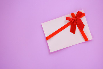 Gift card on red and pink background / Gift card decorated with red ribbon bow to Merry Christmas Holiday Happy new year or Valentines day Gift voucher on pink background top view