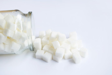 Glass bottle of sugar cubes on white.