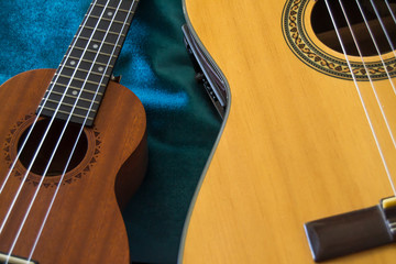 Ukulele near acoustic guitar with blue background