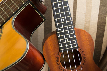 ukulele and acoustic guitar with brown striped background