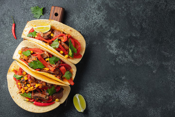 Mexican tacos with beef, vegetables and salsa. Tacos al pastor on wooden board on black background....