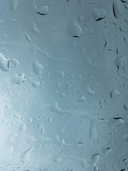 Huge drops of rain on glass, rain drops on clear glass roof of a car