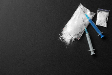 Flat lay composition with cocaine and syringes on dark background. Space for text