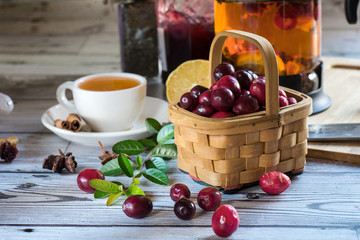 Hot spicy lingonberry or cranberry tea in cup, rustic background