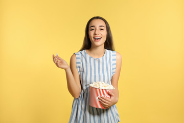Woman with popcorn during cinema show on color background