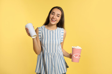 Woman with popcorn and beverage during cinema show on color background