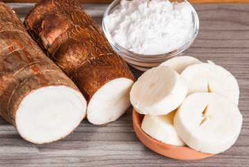 Raw cassava tuber on wooden background - Manihot esculenta