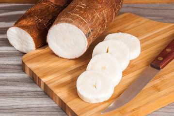 Fototapeta na wymiar Raw cassava tuber on wooden background - Manihot esculenta
