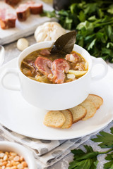 Thick pea soup with smoked meats in a white plate