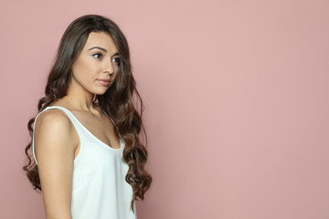 Fototapeta premium Beautiful woman with shiny wavy hair on color background. Space for text