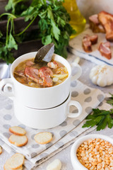 Thick pea soup with smoked meats in a white plate