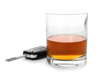 Glass of alcohol and car key on white background. Responsible driving concept