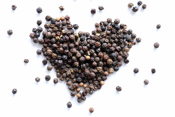 Heart made of black peppercorns on white background