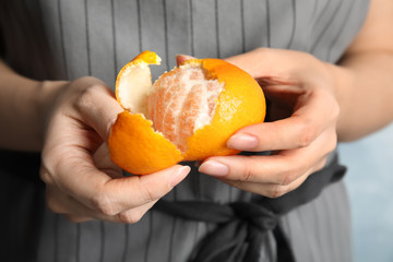 Woman peeling ripe tangerine, closeup. Citrus fruit
