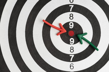 Business goals or financial target, green and red arrow pointing at red dot center of black and white circle dartboard with score numbers