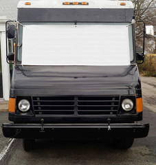 Front view of stationary black food truck with blank white banner stretched across windshield. Copy space.
