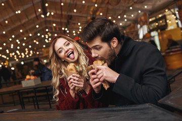 Close-up of young couple are eating sandwiches at the street food market.