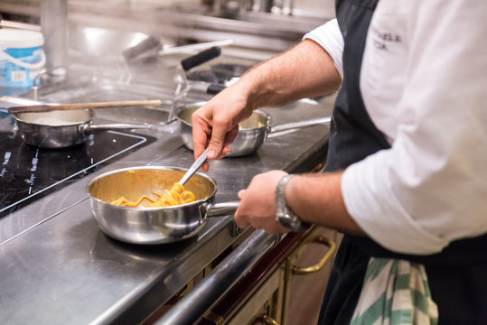 cuoco mescola spaghetti nella pentola